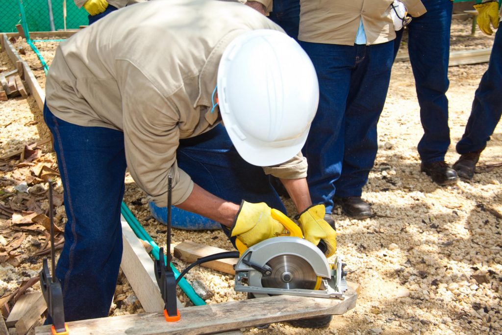 men looking the the man cutting up a piece of wood